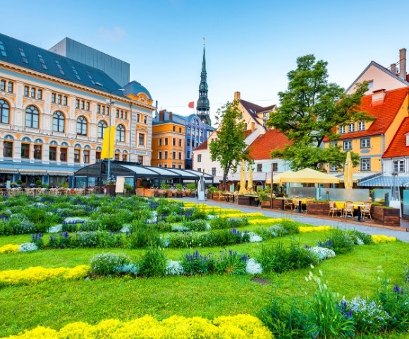 A vibrant European cityscape with ornate historical buildings, a lush garden in the foreground, and colorful facades under a clear blue sky, exuding charm.