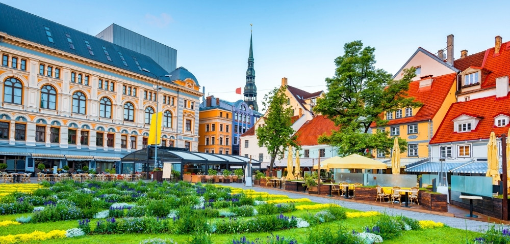 A vibrant European cityscape with ornate historical buildings, a lush garden in the foreground, and colorful facades under a clear blue sky, exuding charm.