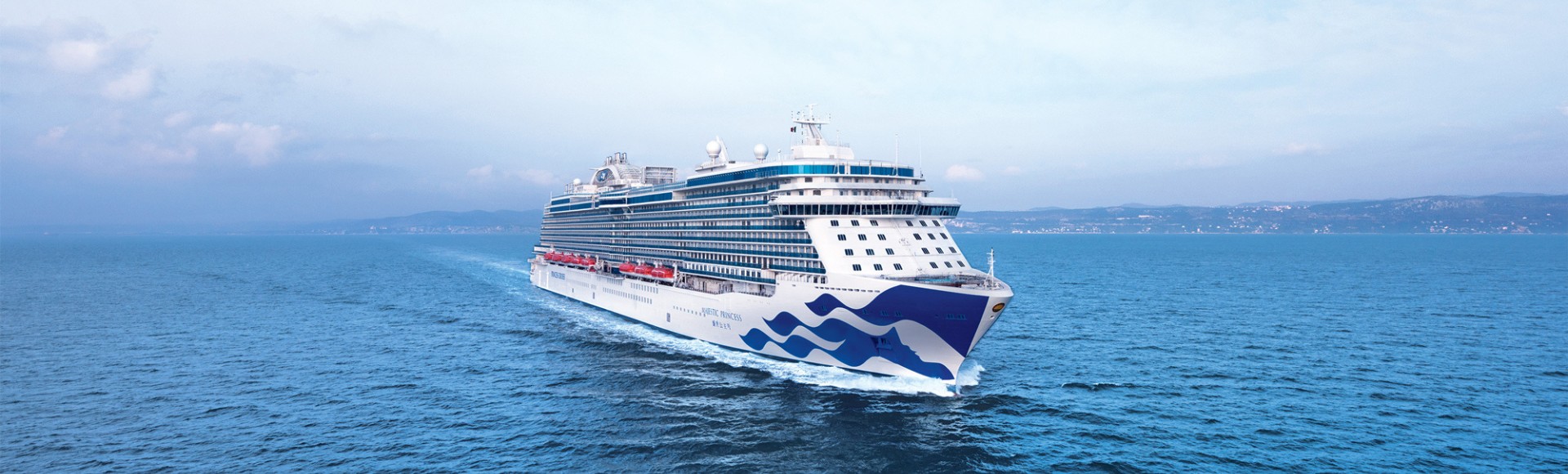 A large cruise ship sails across a calm blue ocean under a lightly clouded sky. The ship's design is modern, evoking a sense of adventure and tranquility.