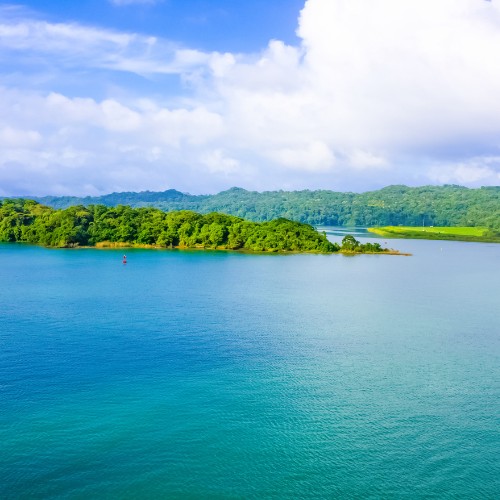 A serene landscape of a vibrant turquoise lake bordered by lush green islands under a partly cloudy sky, evoking tranquility and natural beauty.