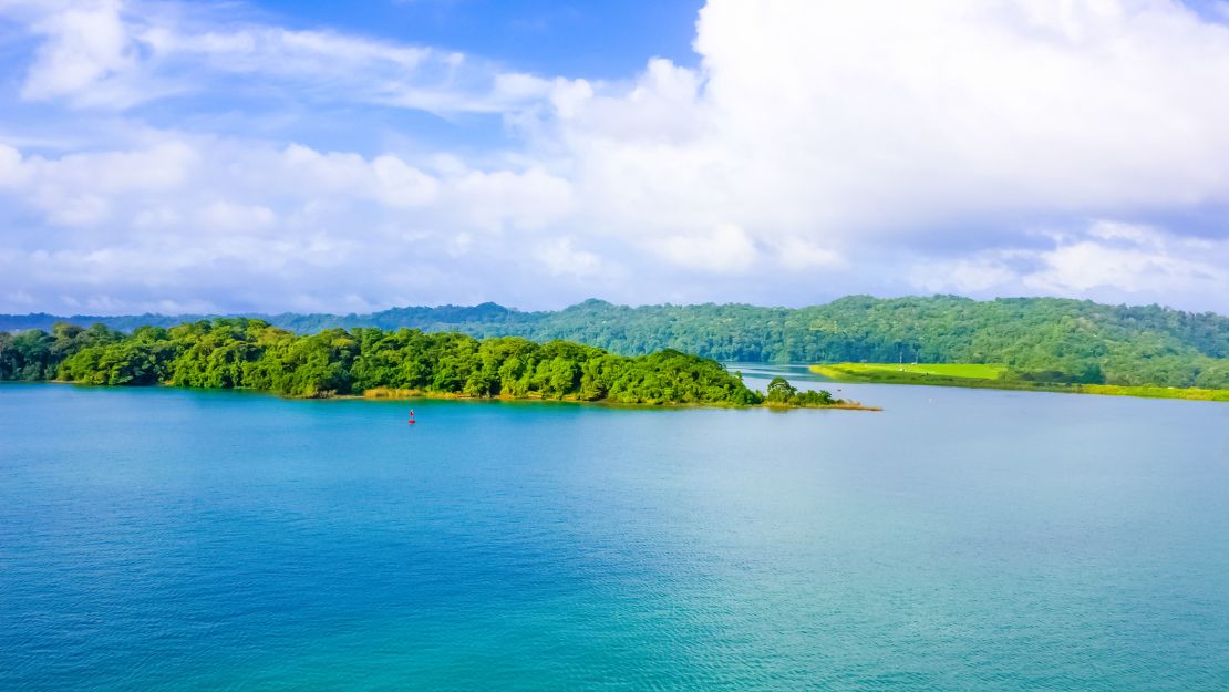 A serene landscape of a vibrant turquoise lake bordered by lush green islands under a partly cloudy sky, evoking tranquility and natural beauty.