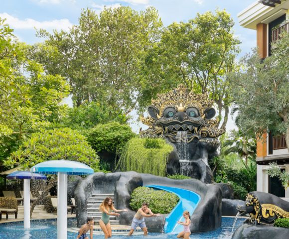 Ornate sculpture with a playful face over a waterfall and water slide in a lush, green garden. Vibrant, whimsical, and inviting atmosphere.