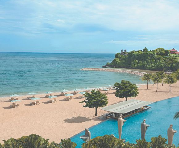 A serene beach scene with turquoise waters and a sandy shore lined with white lounge chairs and umbrellas. Lush greenery and a tranquil pool enhance the coastal vibe.