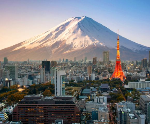 A stunning view of Tokyo skyline at sunset, featuring the illuminated Tokyo Tower in the foreground and majestic Mount Fuji in the background.