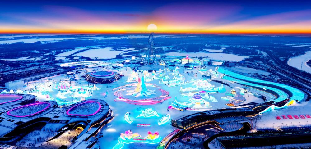 Aerial view of an illuminated winter festival at sunset. Vibrant neon lights form intricate designs on snow, surrounded by dark, snowy fields. Energetic and magical.