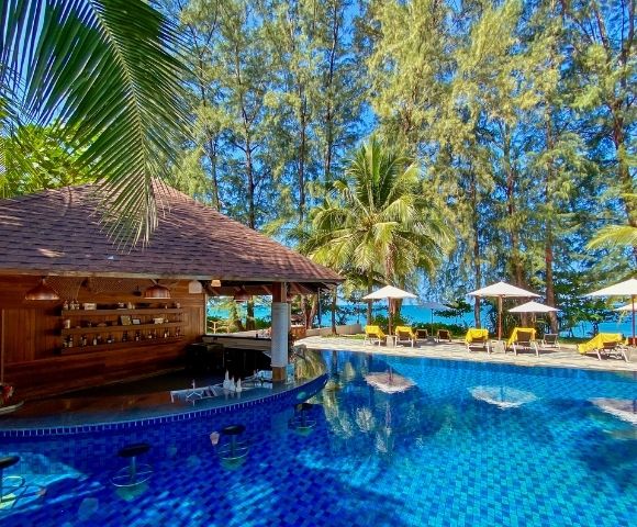 Tropical pool scene with a swim-up bar, surrounded by sun loungers and umbrellas. Palm trees and a serene ocean view create a relaxed, sunny atmosphere.
