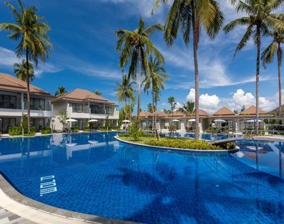 Luxurious resort pool under a vibrant blue sky, surrounded by tall palm trees and elegant villas. The scene conveys a relaxing and serene tropical ambiance.