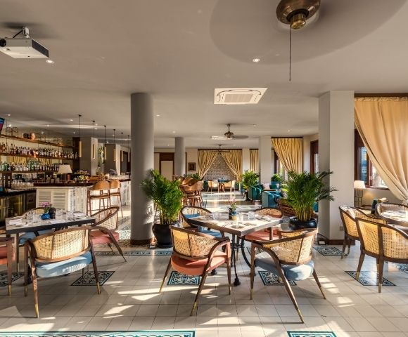 Modern restaurant interior with wooden furniture, potted plants, and soft lighting. Open layout with a warm, inviting atmosphere.