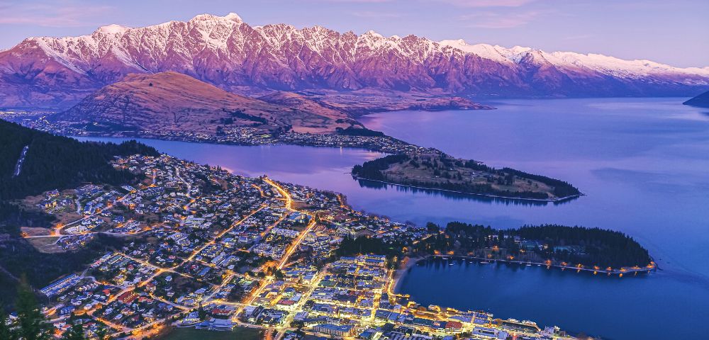 Scenic view of Queenstown, New Zealand, showcasing mountains and a lake under a clear blue sky.