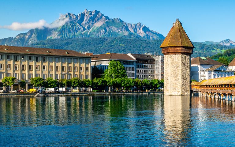 Lucerne, Switzerland, showcasing its picturesque lake, mountains, and charming architecture under a clear blue sky.
