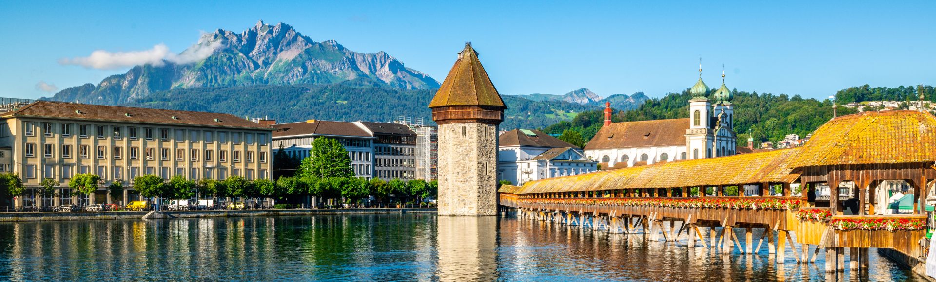 Lucerne, Switzerland, showcasing its picturesque lake, mountains, and charming architecture under a clear blue sky.