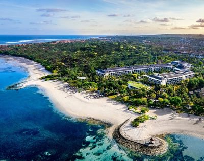 Aerial view of a coastal resort surrounded by lush greenery. Pristine beaches and turquoise waters evoke a serene, tropical paradise.