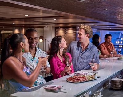 A group of friends enjoying drinks and conversation at a stylish bar, surrounded by an elegant ambiance and delicious appetizers.