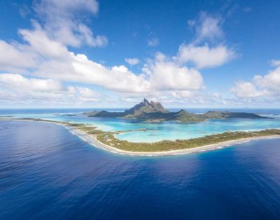 Aerial view of a tropical island with a mountain surrounded by turquoise water.