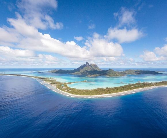 Aerial view of a tropical island with a mountain surrounded by turquoise water.