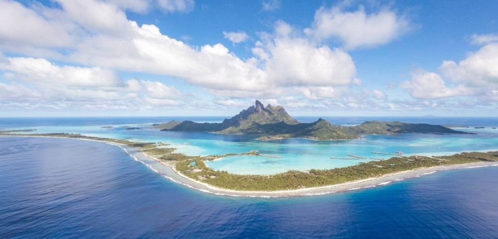 Aerial view of a tropical island with a mountain surrounded by turquoise water.