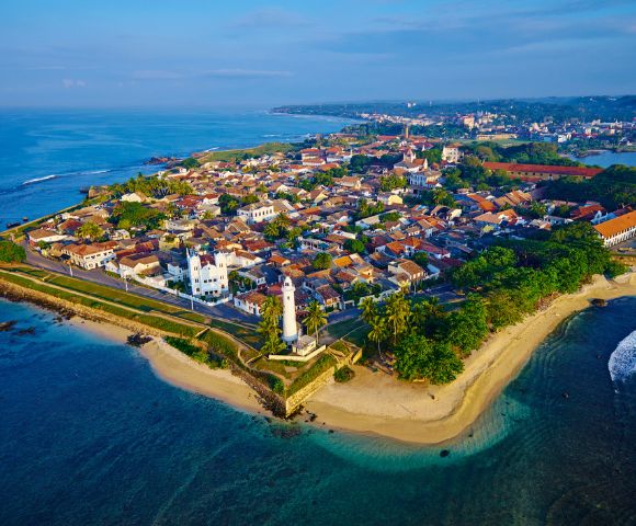 Aerial view of a large rock fortress rising above dense green forest.