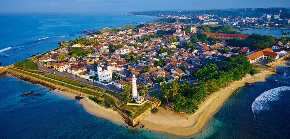 Aerial view of a large rock fortress rising above dense green forest.