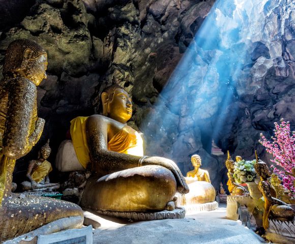 Sunlight shining into a cave temple illuminating Buddha statues