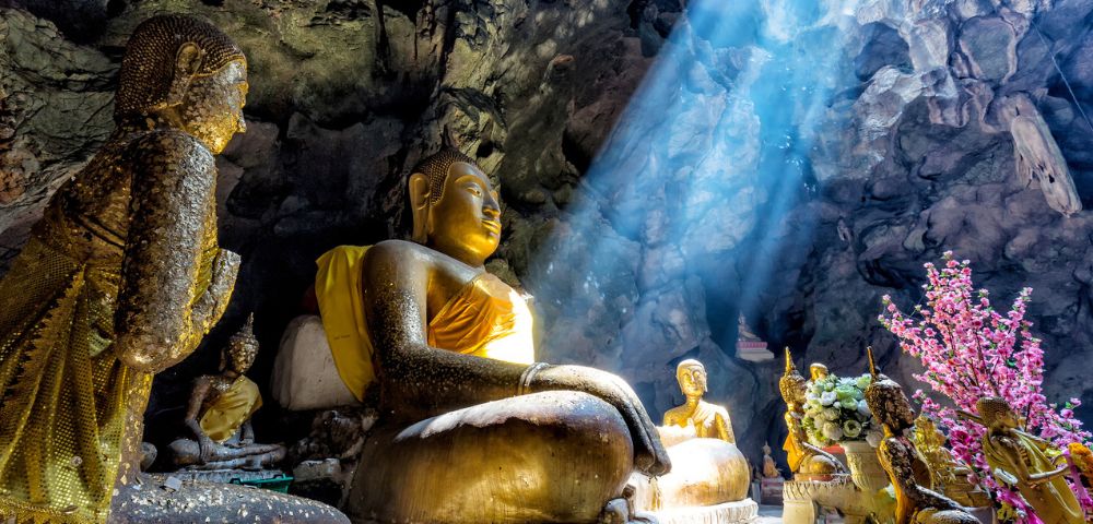 Sunlight shining into a cave temple illuminating Buddha statues