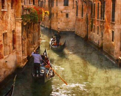 Two gondolas navigate a narrow Venetian canal, guided by gondoliers. Sunlight bathes the aged, warm-toned buildings, creating a serene, nostalgic ambiance.
