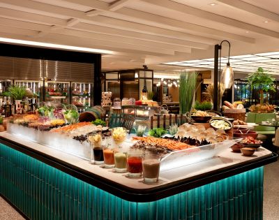 Luxurious buffet with a variety of seafood on ice, colorful salads, and garnishes. Elegant lighting and green-tiled counters create a refined atmosphere.