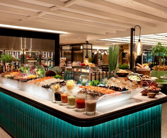 Luxurious buffet with a variety of seafood on ice, colorful salads, and garnishes. Elegant lighting and green-tiled counters create a refined atmosphere.