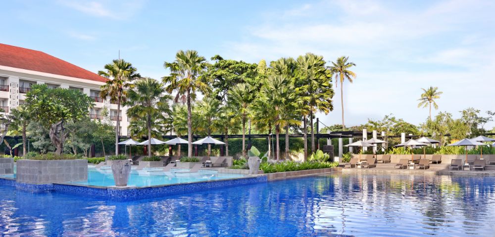 A hotel in Bali, showcasing its stunning architecture and lush tropical surroundings under a clear blue sky.