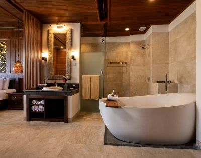Luxurious bathroom with a freestanding white bathtub, adjacent glass shower, and sleek vanity. Warm wood and soft lighting create a calm, spa-like atmosphere.