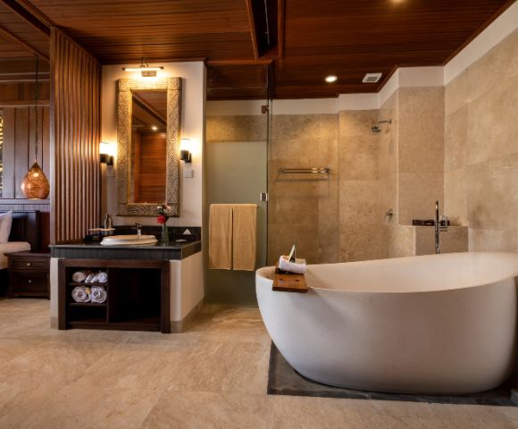 Luxurious bathroom with a freestanding white bathtub, adjacent glass shower, and sleek vanity. Warm wood and soft lighting create a calm, spa-like atmosphere.