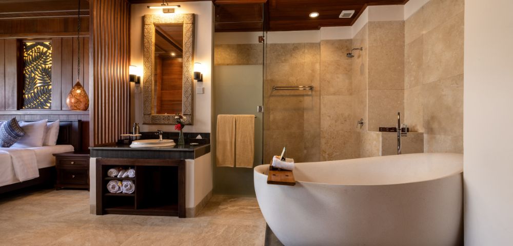 Luxurious bathroom with a freestanding white bathtub, adjacent glass shower, and sleek vanity. Warm wood and soft lighting create a calm, spa-like atmosphere.