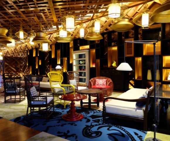 Cozy room with eclectic furniture, including wicker chairs, patterned rugs, and warm lighting. The ambiance is inviting and stylishly rustic.