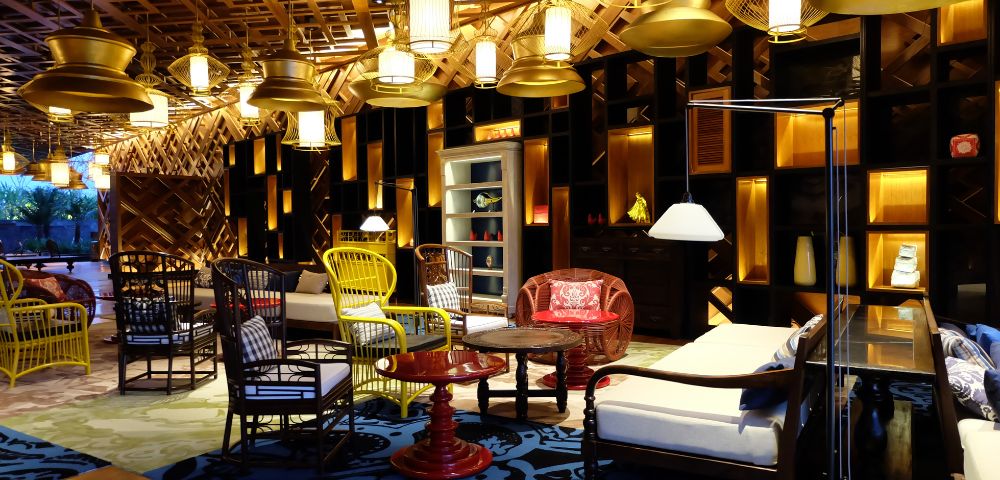 Cozy room with eclectic furniture, including wicker chairs, patterned rugs, and warm lighting. The ambiance is inviting and stylishly rustic.