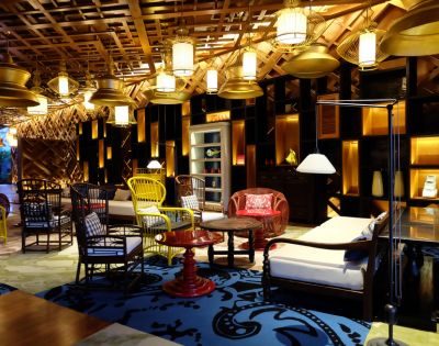 Cozy room with eclectic furniture, including wicker chairs, patterned rugs, and warm lighting. The ambiance is inviting and stylishly rustic.