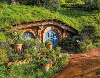 Charming hobbit house with a round blue door set into a grassy hillside. Surrounded by vibrant flowers and plants, evoking a whimsical, tranquil mood.