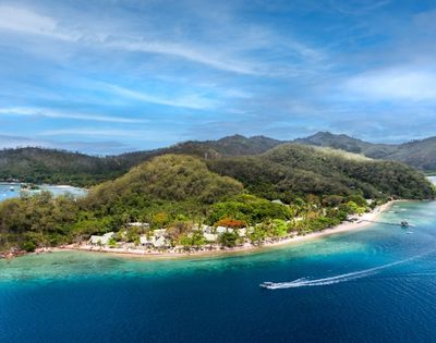 Aerial view of a lush, tropical island surrounded by turquoise ocean. Sandy beaches and distant hills evoke a serene and inviting paradise atmosphere.