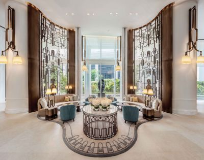 Luxurious hotel lobby with ornate metal screens, elegant seating, and warm lighting. Central floral arrangement on a round table exudes sophistication.