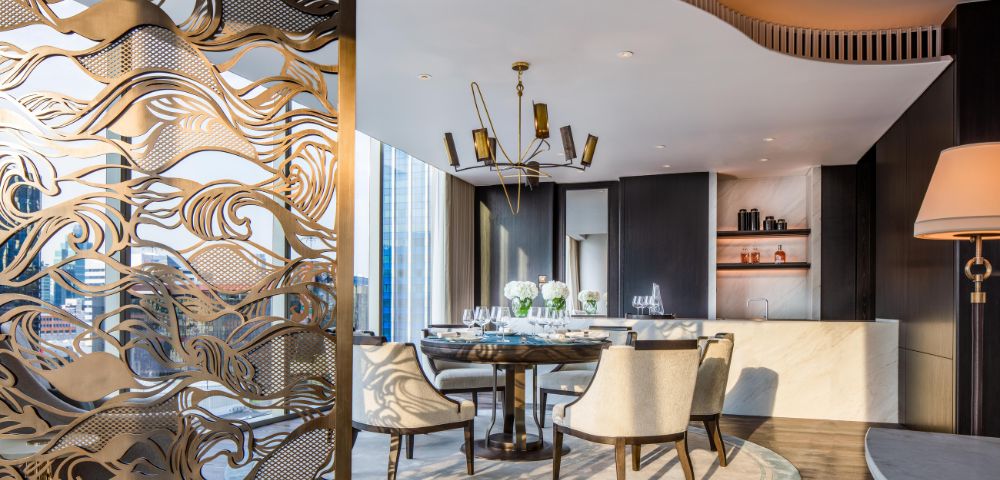 Elegant dining room with a modern chandelier, round table surrounded by white chairs, decorative screen, and a sophisticated ambient reflecting luxury.