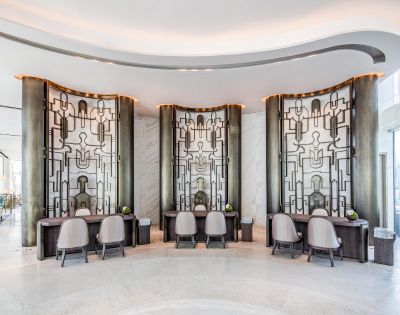 Elegant hotel lobby with modern decor features three artistic, geometric wall panels. Curved desks and chairs add sophistication, while lighting sets a calming tone.