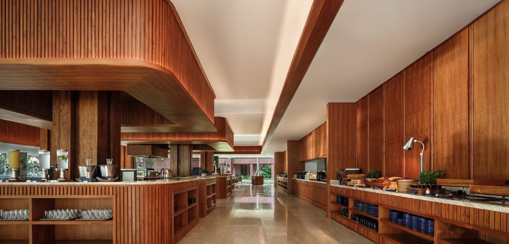 Alt text: Modern kitchen with wooden cabinetry and countertops, featuring sleek recessed lighting. The space is neat, warm, and inviting, with an organized setup.