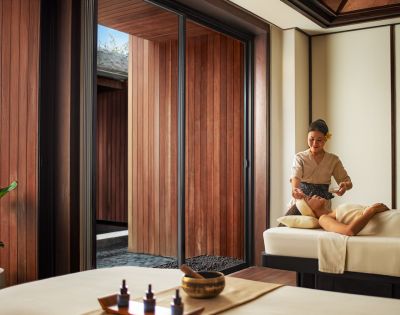 A person receiving a massage in a serene spa setting, with wooden walls and soft lighting. Relaxation and tranquility are emphasized.