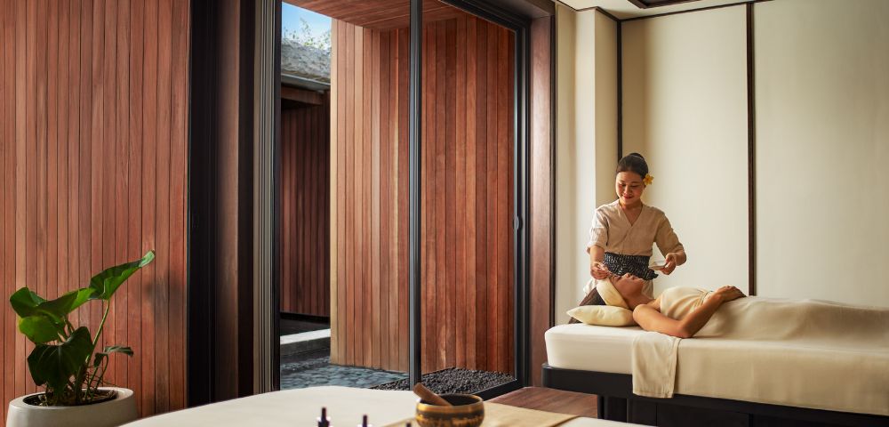 A person receiving a massage in a serene spa setting, with wooden walls and soft lighting. Relaxation and tranquility are emphasized.