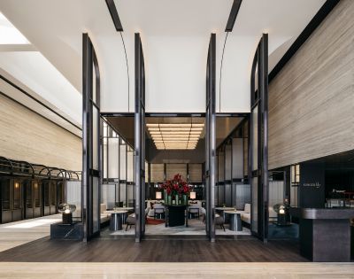 Spacious modern hotel lobby with high ceilings, sleek black partitions, and elegant seating. Red floral centerpiece adds a touch of vibrancy and luxury.