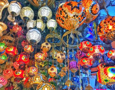 A vibrant display of assorted mosaic lamps in various colors and patterns hanging from ornate fixtures, creating a colorful and lively atmosphere.