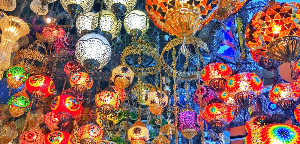 A vibrant display of assorted mosaic lamps in various colors and patterns hanging from ornate fixtures, creating a colorful and lively atmosphere.