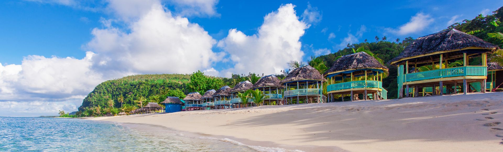 Aerial view of a tropical island resort surrounded by clear blue water and lush greenery.