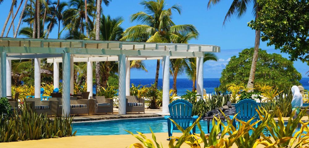 A sunny pool area featuring lounge chairs and palm trees, perfect for relaxation and enjoying the outdoors.