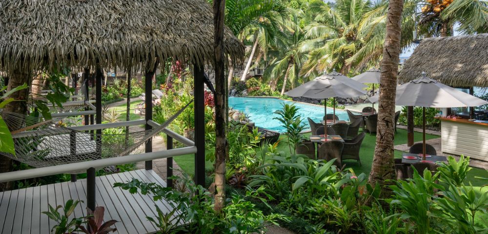 Aerial view of a tropical resort featuring a sparkling pool surrounded by lush palm trees.
