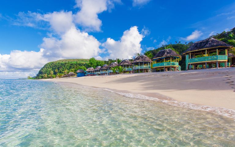 Aerial view of a tropical island resort surrounded by clear blue water and lush greenery.