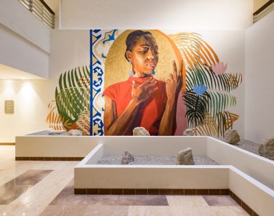 A vibrant mural depicts a thoughtful woman in a red shirt, surrounded by abstract leaves and geometric patterns. The scene is situated in a modern, serene atrium.